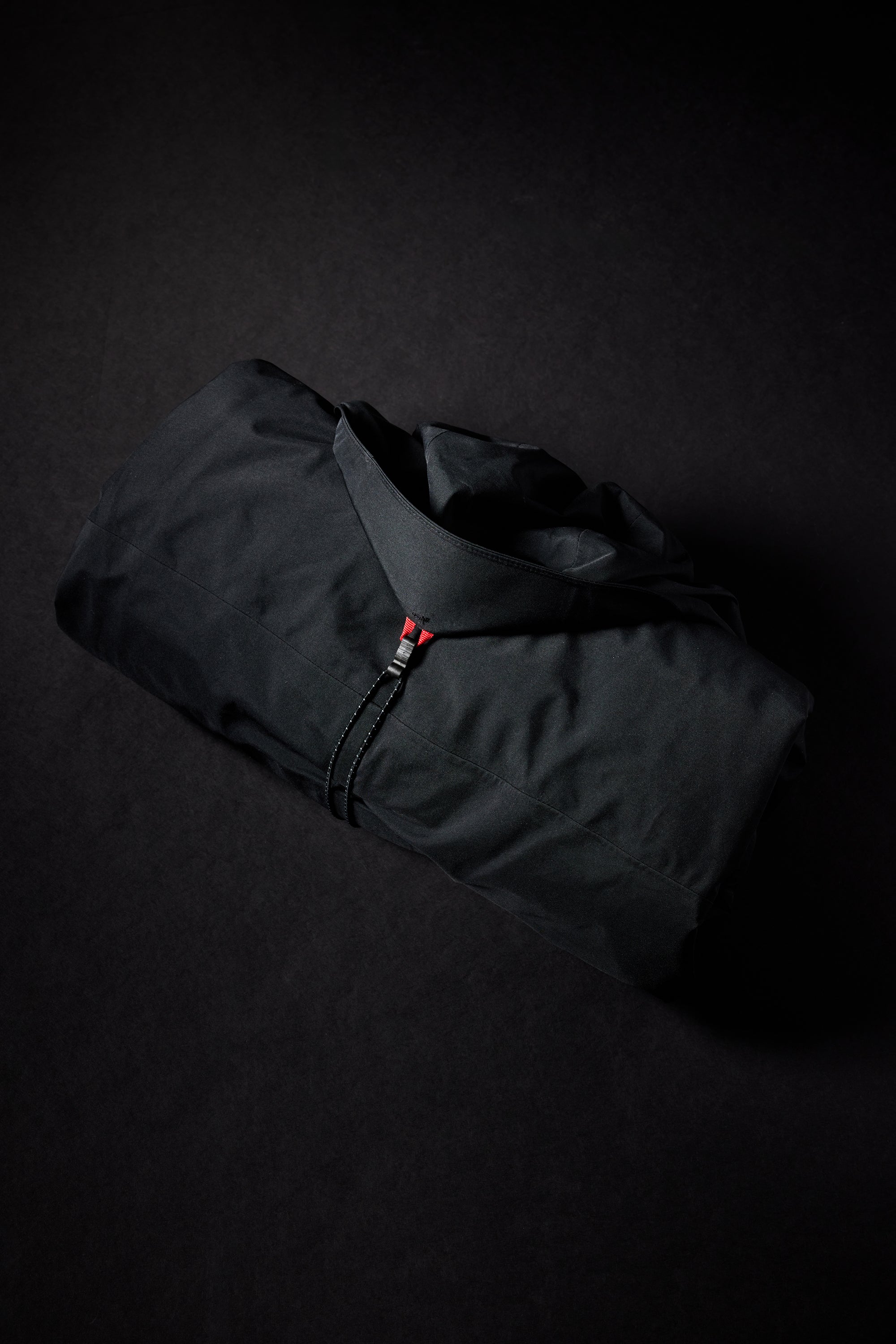 The 686 Women's GORE-TEX Skyline Shell Jacket 2025 is black with an insulated hood and a red zipper pull.