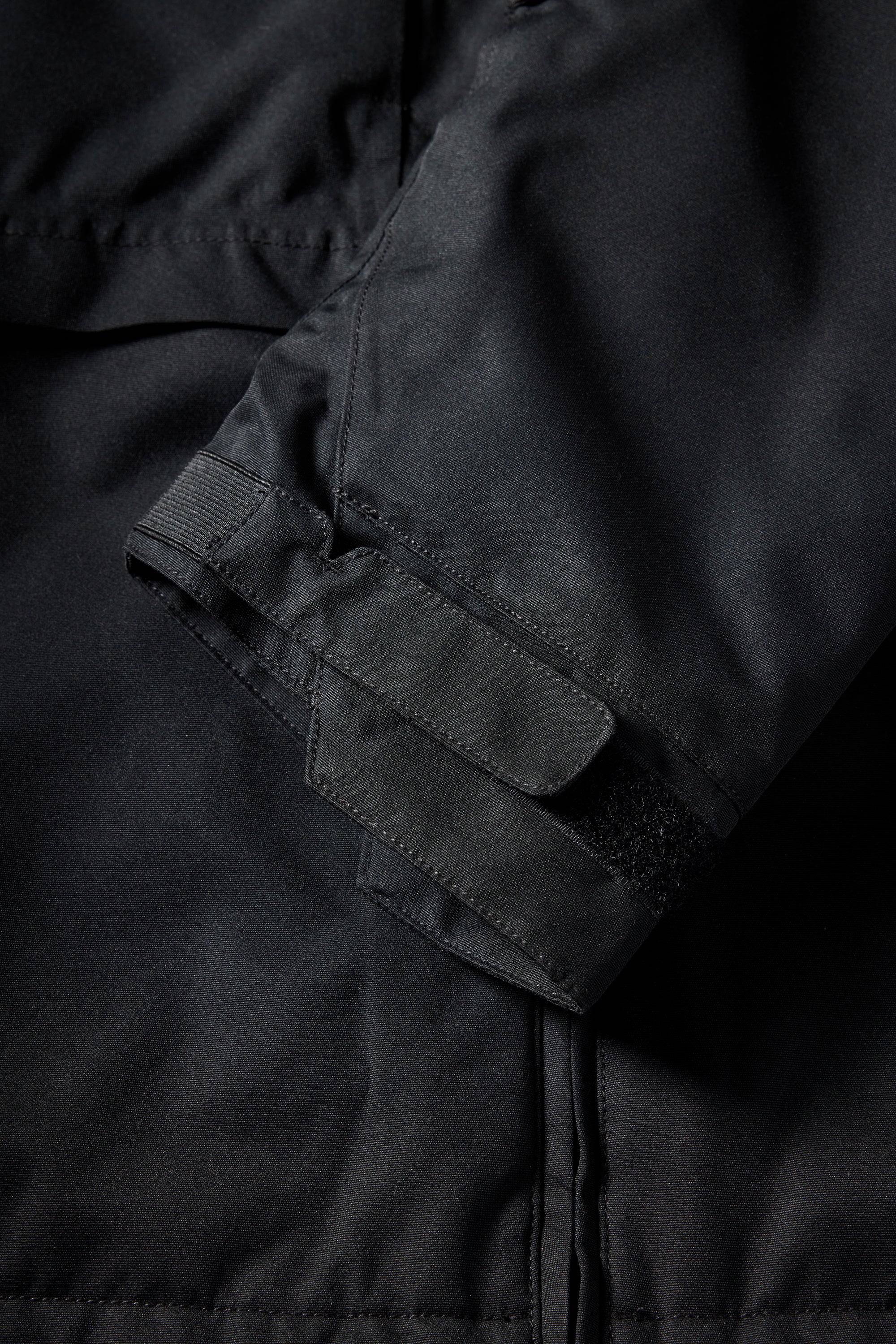 The 686 women's outline shell anorak has a water-repellent black outer layer with a white zipper and two front pockets.