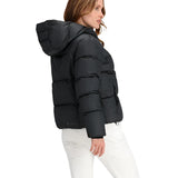Obermeyer Women's Calypso Down Jacket 2025 - A black down jacket with a hood, worn by a woman with long brown hair and white pants.