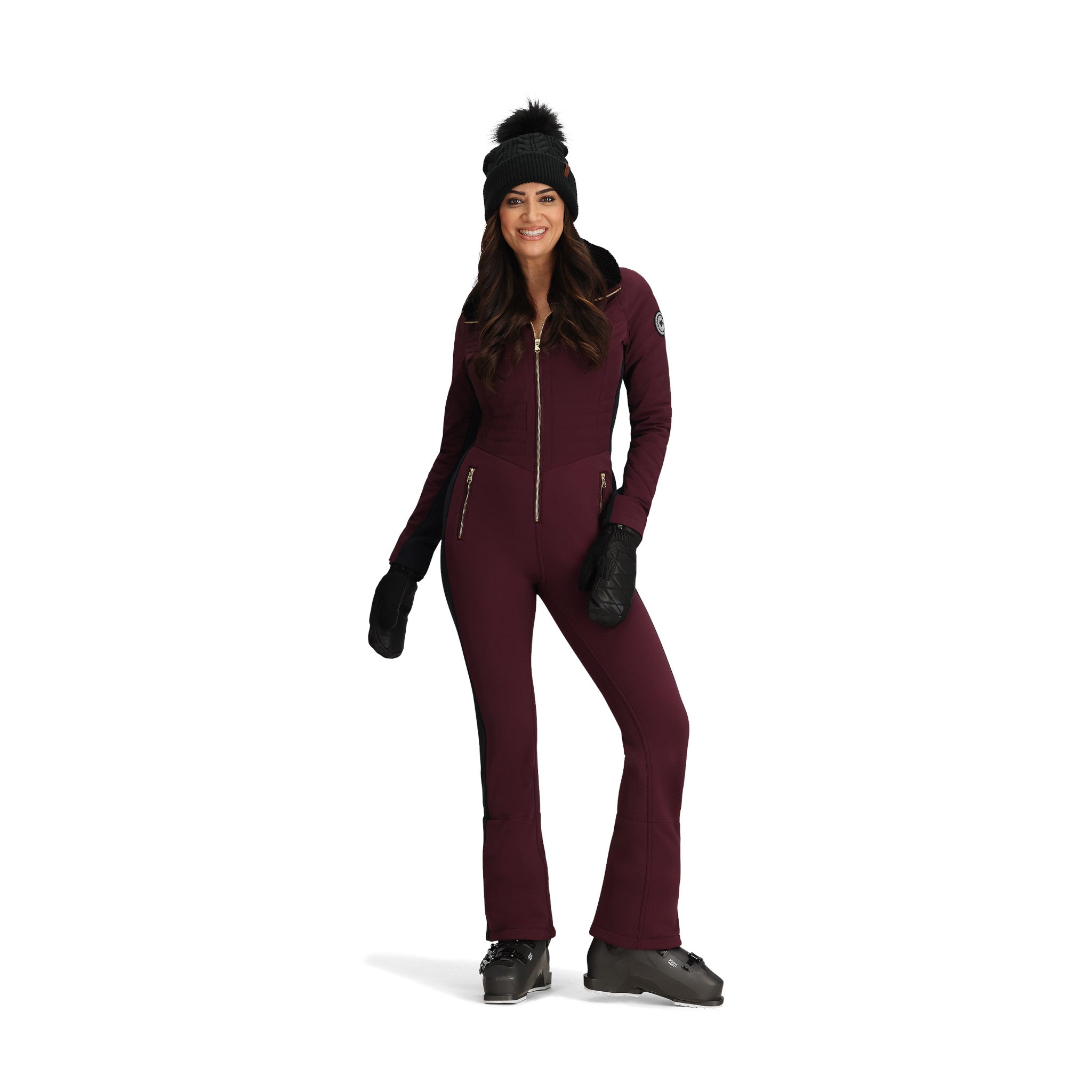 Obermeyer Women's Katze Insulated Suit 2025 - A burgundy insulated snowsuit with a zippered front and gold zipper pulls, worn by a model posing in front of a white background.