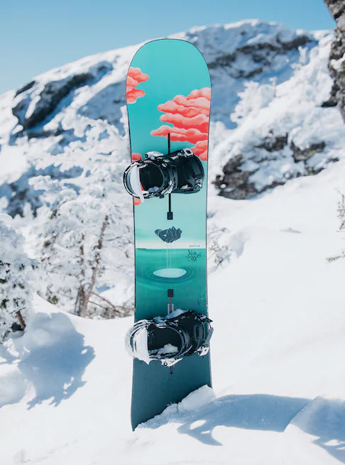 Burton Women's Yeasayer Snowboard 2025 - A blue snowboard with a pink cloud design on top of a snowy mountain.