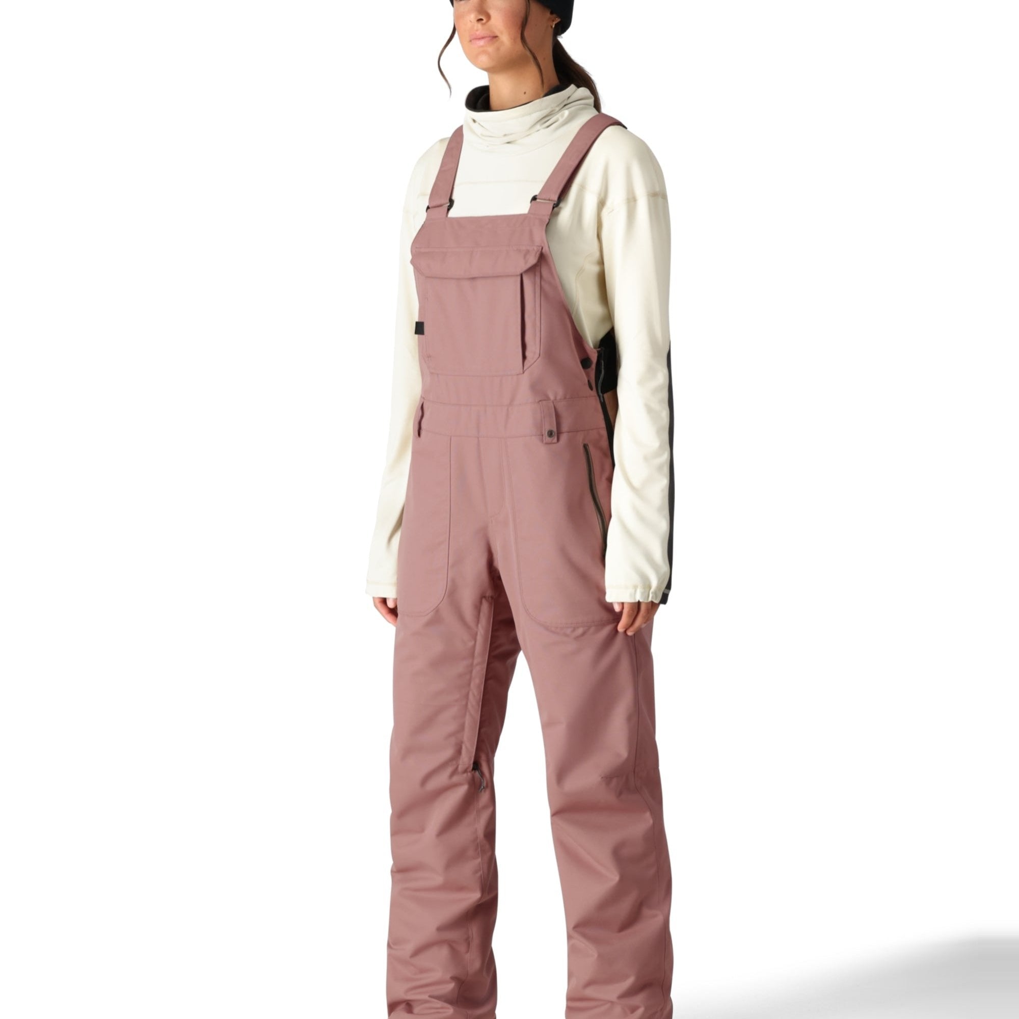 The 686 Black Magic Insulated Bib Pants are showcased from the side view, highlighting their black color and zippered pockets.