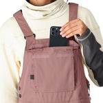 The 686 Black Magic bib overall in black has an insulated hood and front zip closure.