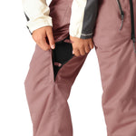 The 686 Women's Black Magic Insulated Bib 2025 is primarily pink with black accents and features an insulated hood.