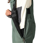 The 686 Women's Black Magic Insulated Bib 2025 bib overall has an all-black exterior with a black zipper and a black BOA dial on the left side.