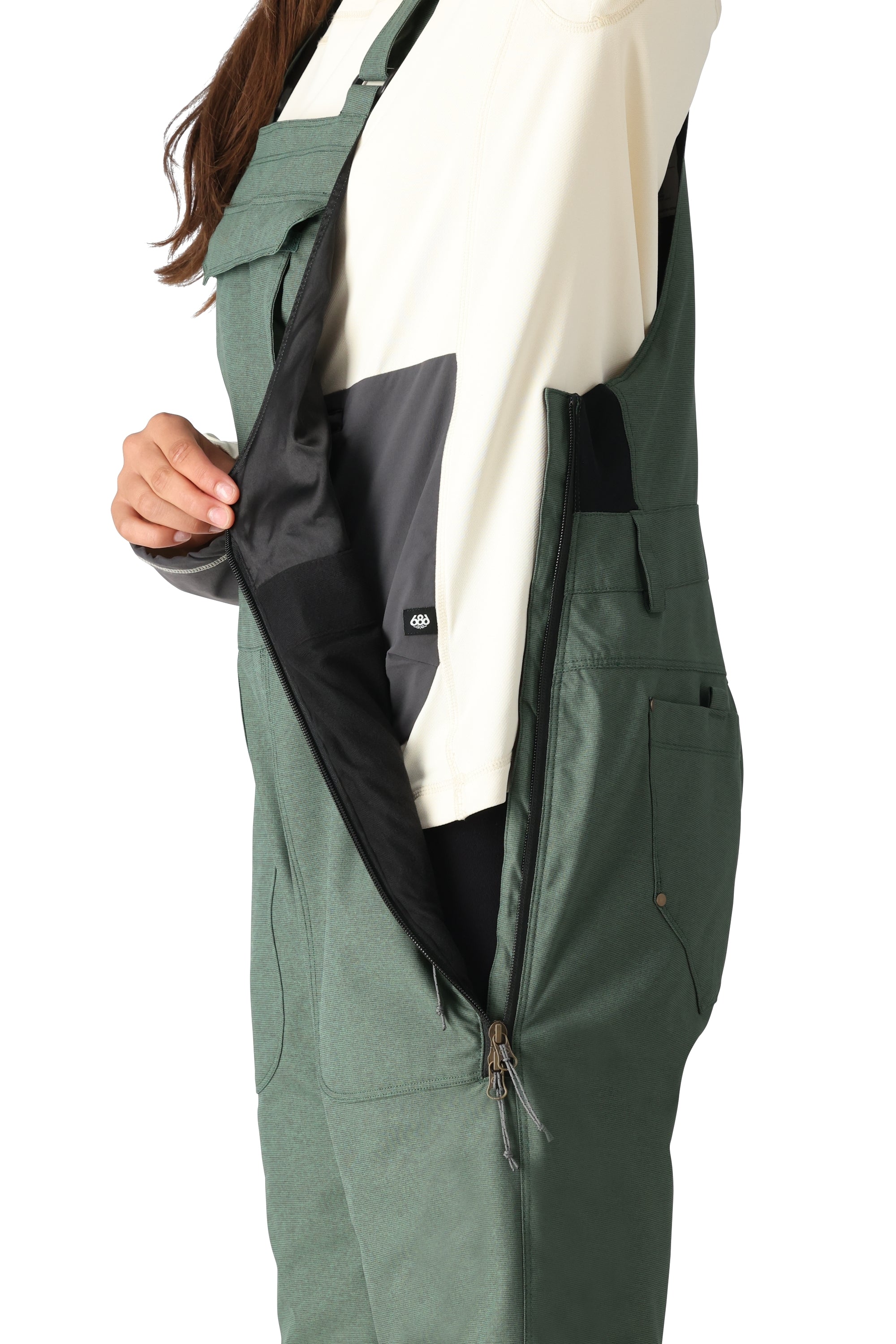 The 686 Women's Black Magic Insulated Bib 2025 bib overall has an all-black exterior with a black zipper and a black BOA dial on the left side.