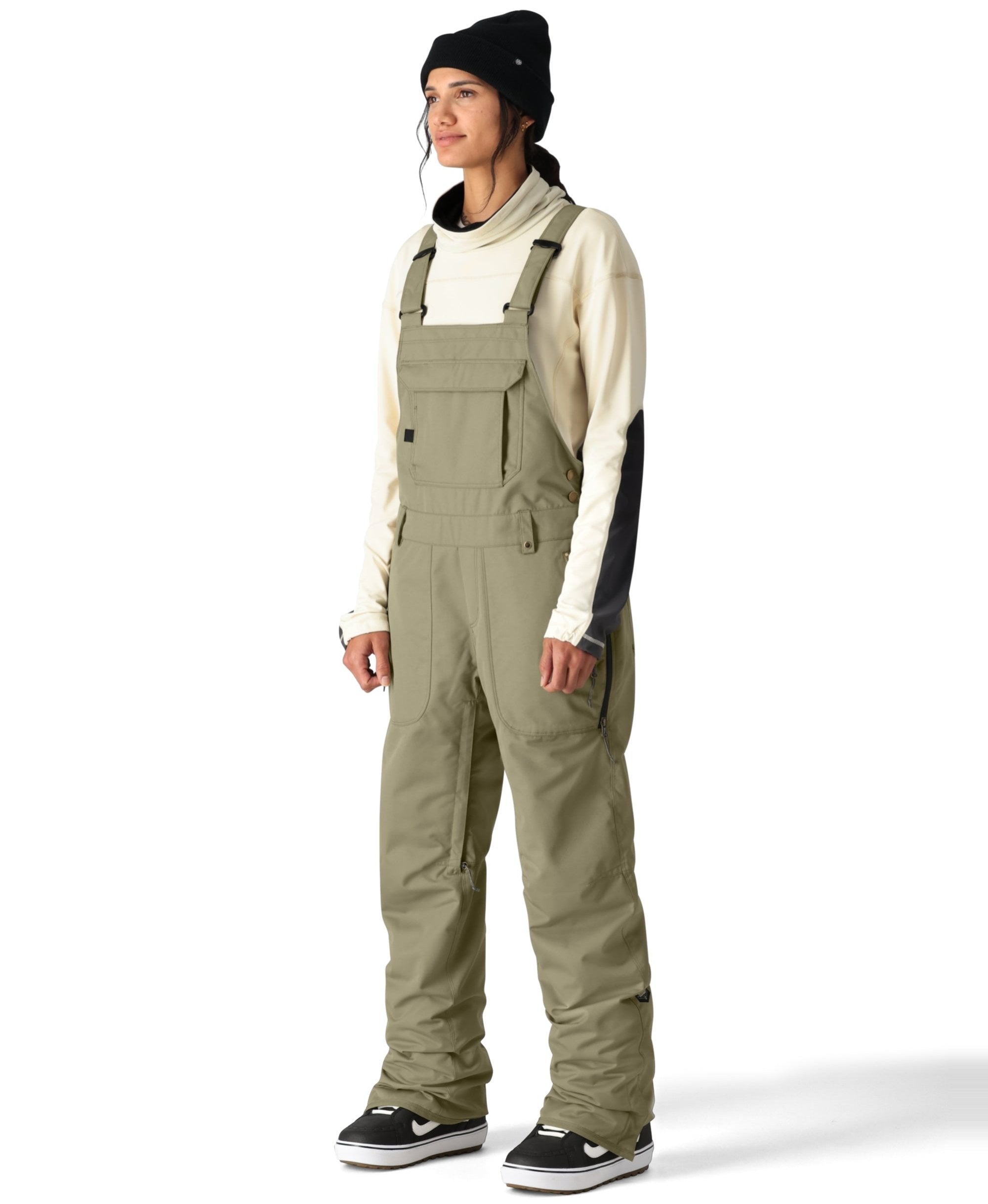 The 686 Women's Black Magic Insulated Bib features a light gray color with black accents and appears to be adjustable at the shoulders.