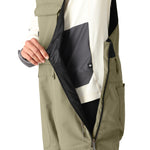 The 686 Women's Black Magic Insulated Bib 2025 is shown in black with an adjustable waistband and two zippered pockets.