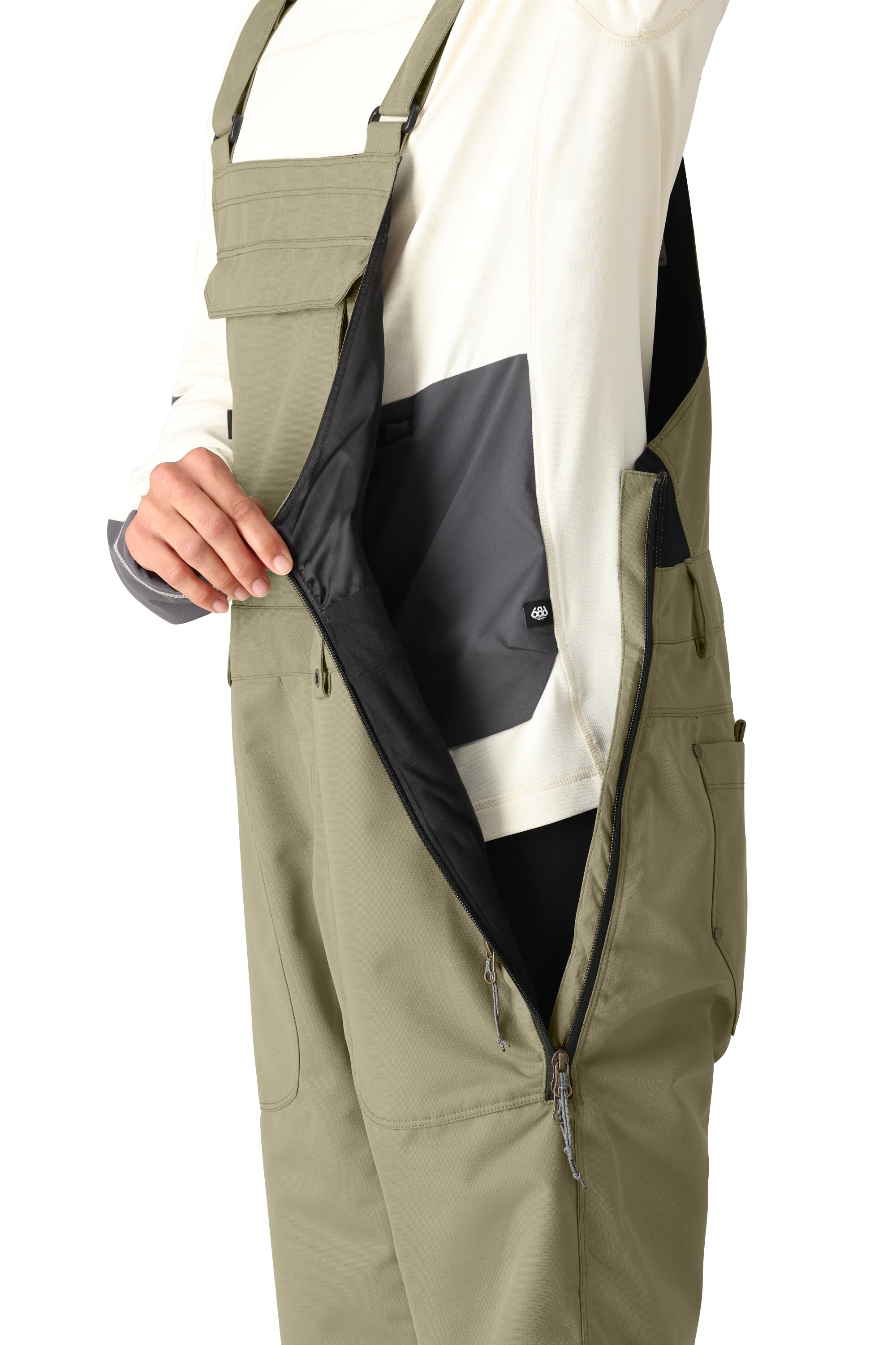 The 686 Women's Black Magic Insulated Bib 2025 is shown in black with an adjustable waistband and two zippered pockets.