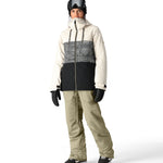 The 686 Black Magic insulated bib pants are primarily black with a geometric pattern on the front in shades of white and grey.