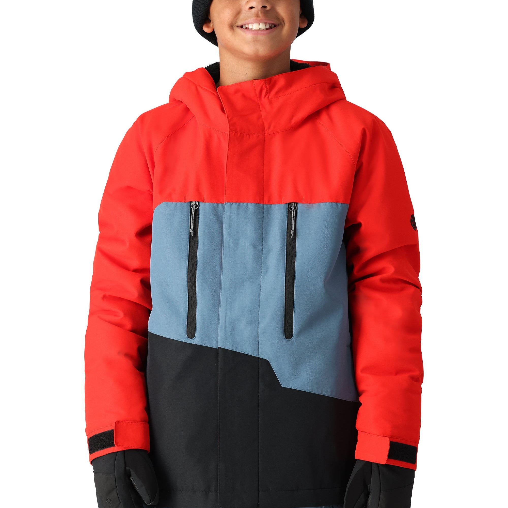 The 686 Youth GEO Insulated Jacket has a red and blue color scheme with a black front panel and two zippered pockets.