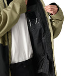The 686 Foundation Insulated Jacket 2025, as seen in this front view, is olive green with an insulated hood and a zippered chest pocket.