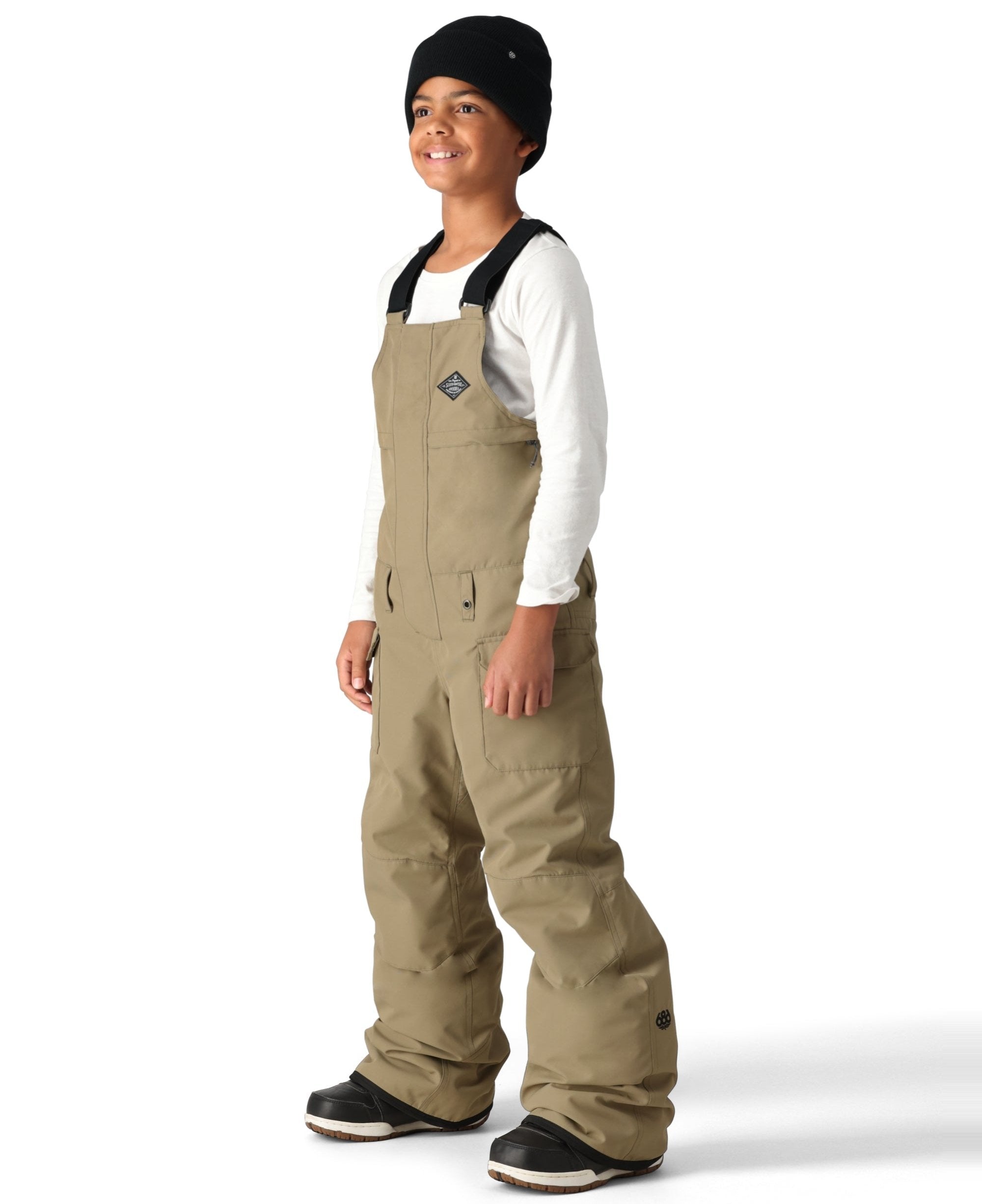 The 686 Boy's Frontier Insulated Bib appears to be tan with black accents and has an adjustable waist strap.