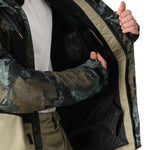 The 686 Geo Insulated Jacket 2025 has an olive green and brown camouflage pattern with tan accents on the trim.