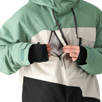 The 686 Geo Insulated Jacket 2025 has a predominantly green color scheme with a white panel on the front and black accents, featuring a drawstring hood and zippered pockets.