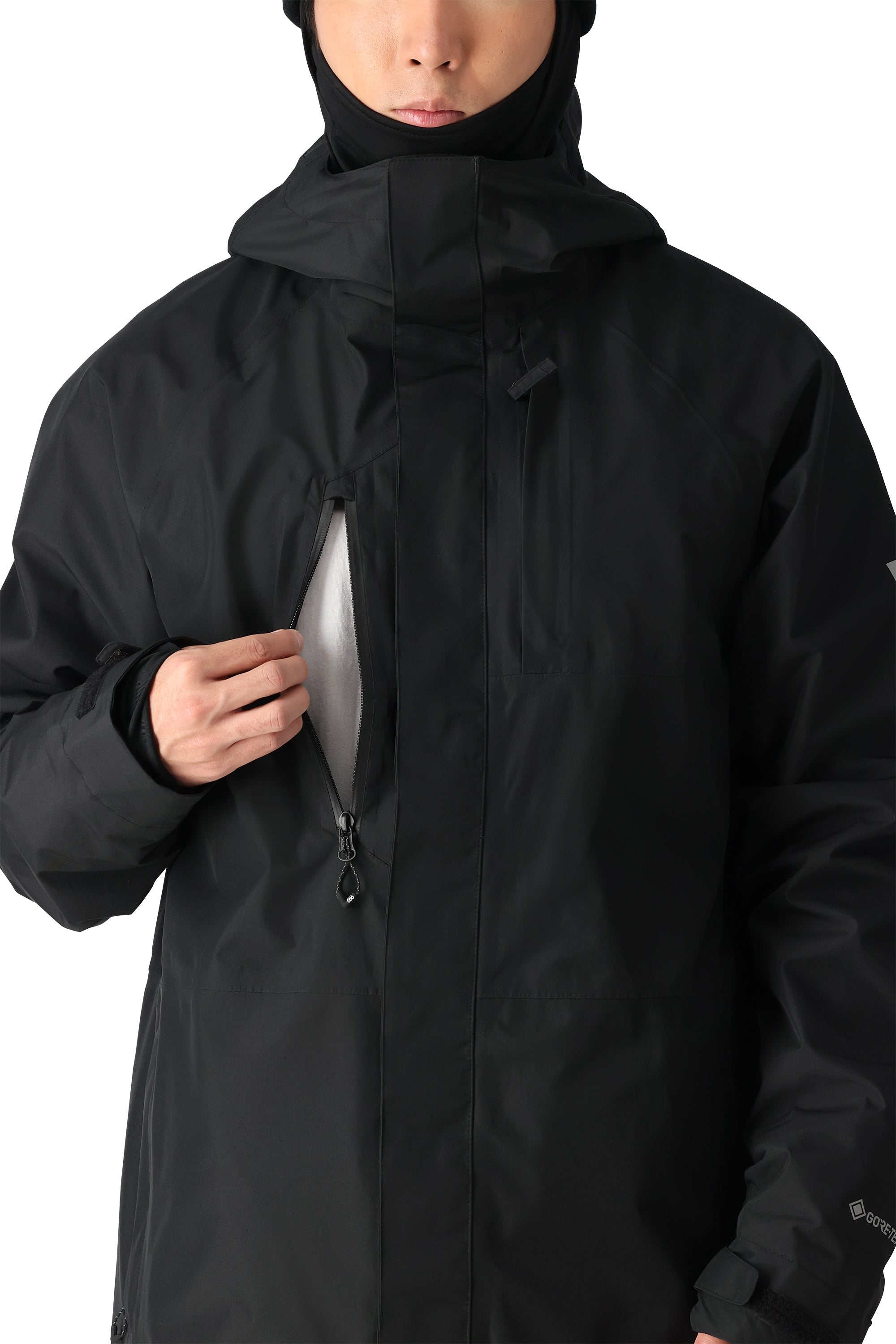 The 686 GORE-TEX Core Shell Jacket 2025 is black with a white fleece lining visible through the zipper and has a high collar.