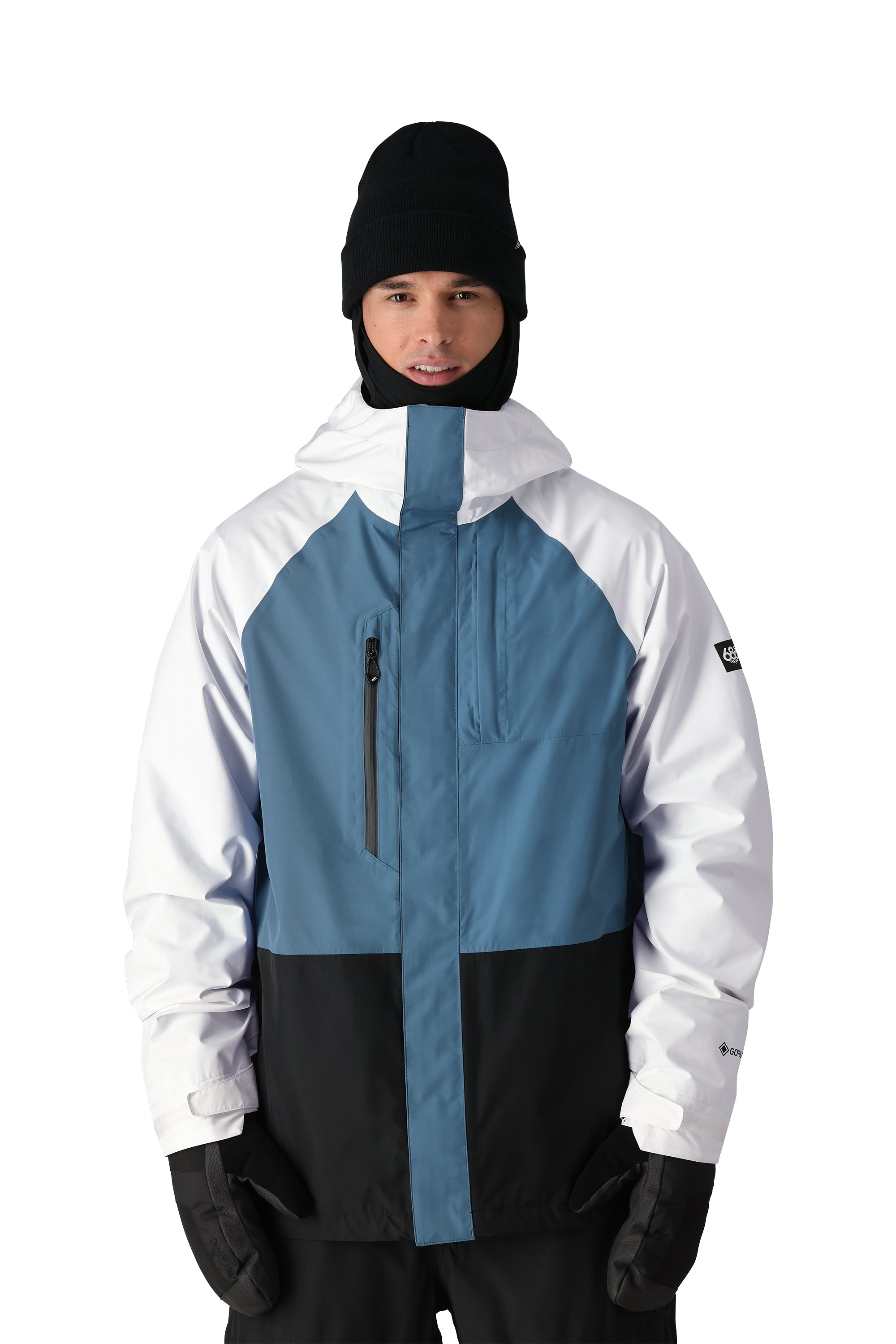The 686 Gore-Tex Core Shell Jacket in black and white has a blue panel on the chest area with two zippered pockets.