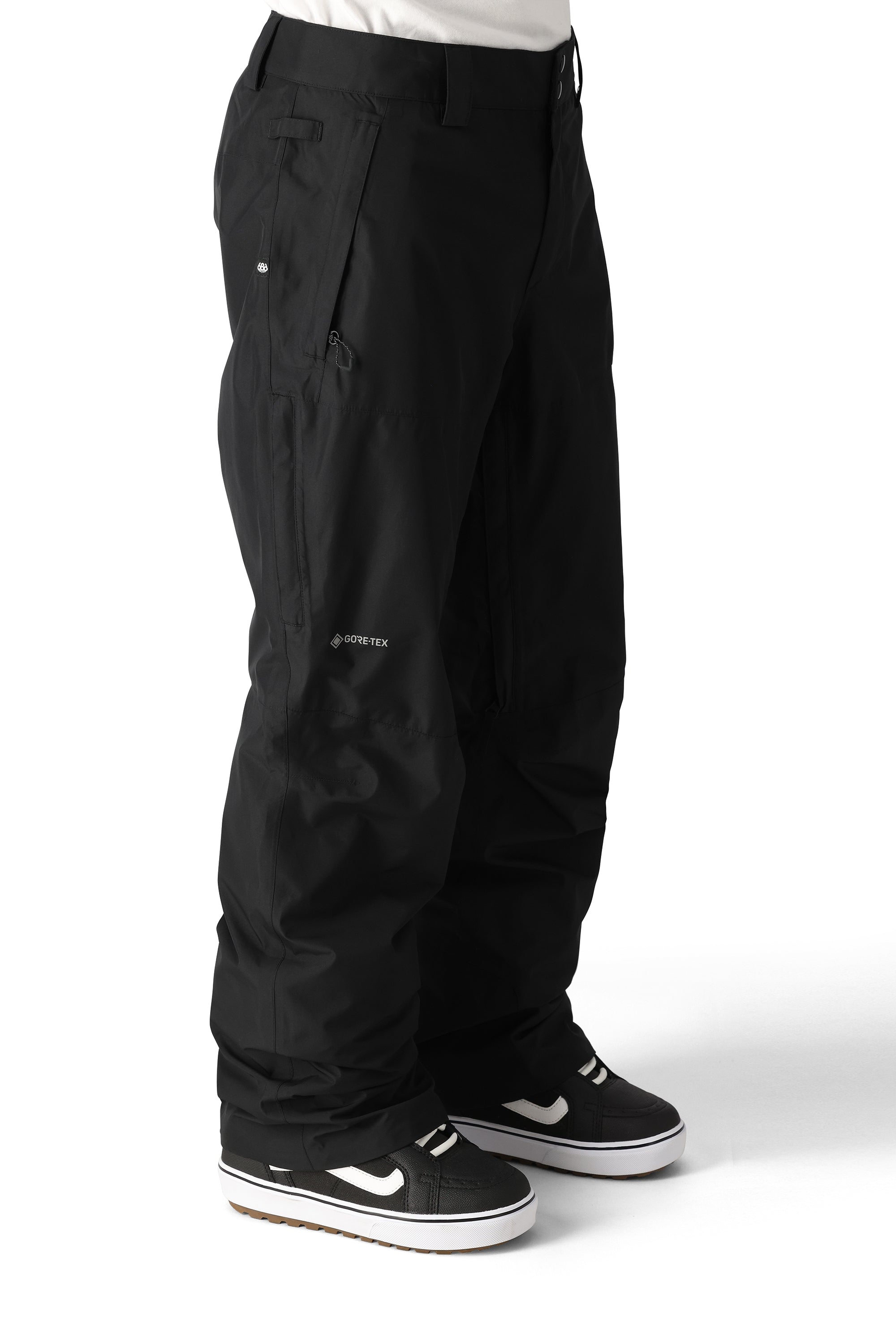 The 686 Men's GORE-TEX Core Shell Pant 2025 is black with a zippered pocket on the right thigh and a snap button closure at the waist.