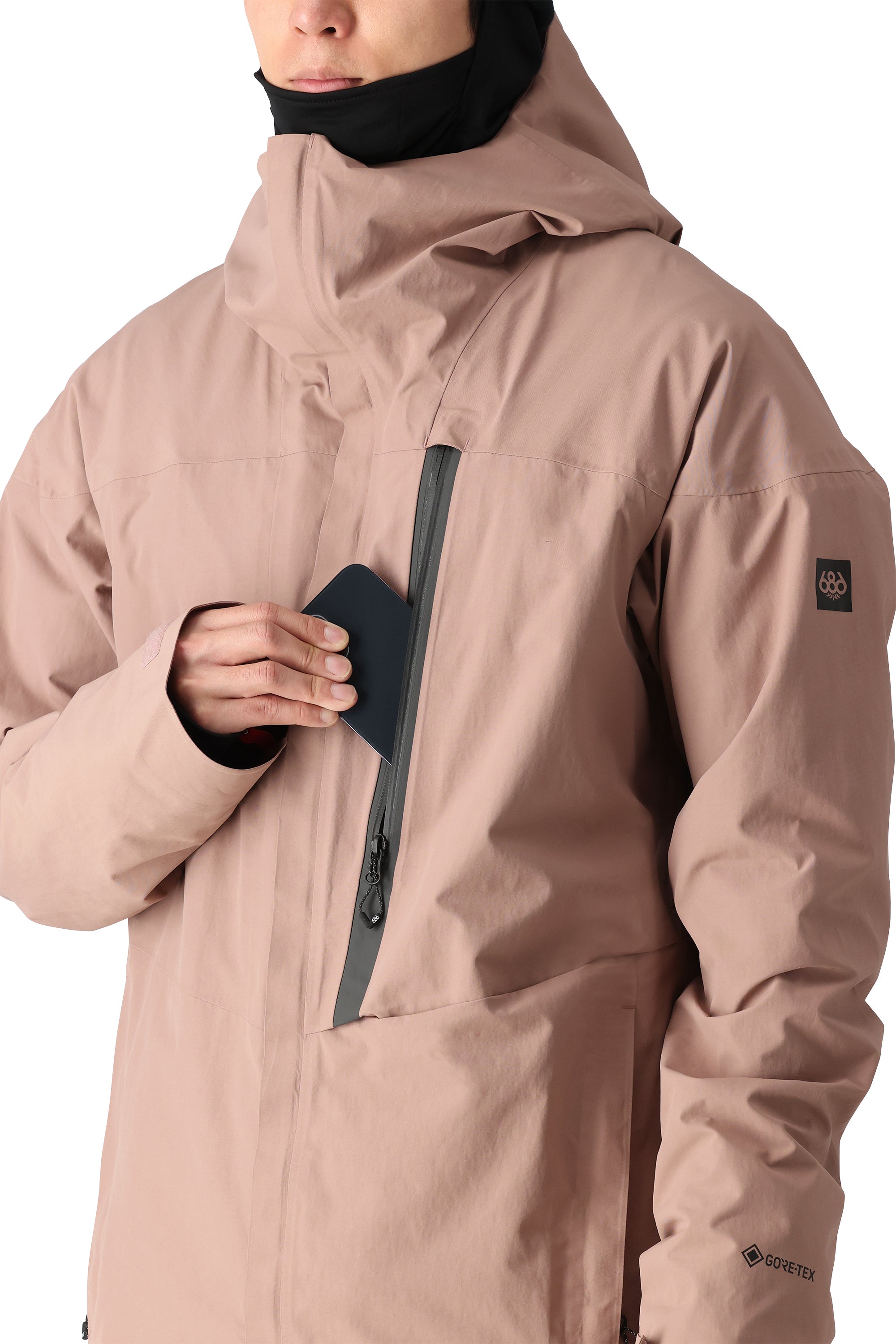 The 686 Gore-Tex GT shell jacket in light pink has an insulated hood and appears to be unzipped.