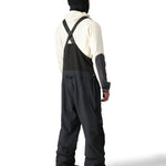 The 686 men's Gore-Tex stretch dispatch bib 2025 is predominantly black with white accents and a reflective logo on the left thigh.