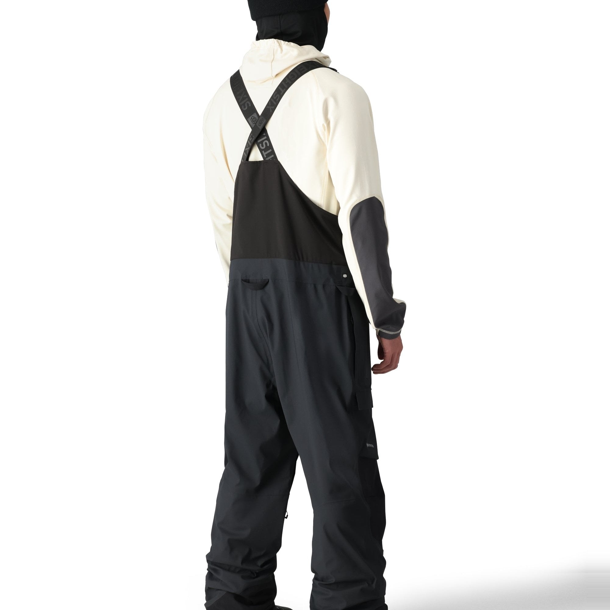 The 686 men's Gore-Tex stretch dispatch bib 2025 is predominantly black with white accents and a reflective logo on the left thigh.