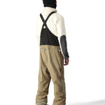 The 686 Gore-Tex Stretch Dispatch Bib pants are primarily black with tan accents and have two zippered front pockets.