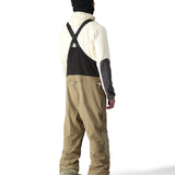 The 686 Gore-Tex Stretch Dispatch Bib pants are primarily black with tan accents and have two zippered front pockets.
