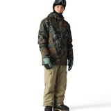 The 686 Hydra Thermagraph Jacket in brown and green camouflage pattern has a hood and appears to be zipped up.