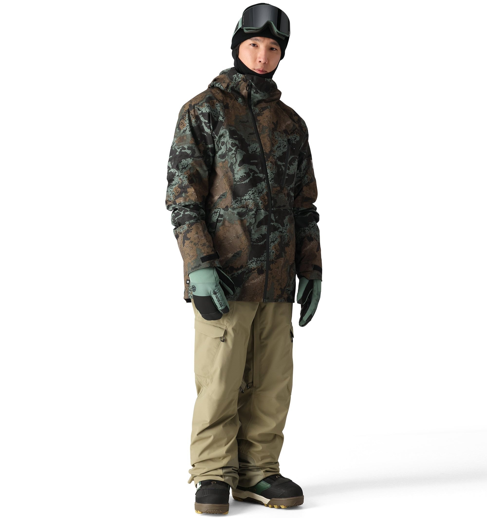 The 686 Hydra Thermagraph Jacket in brown and green camouflage pattern has a hood and appears to be zipped up.