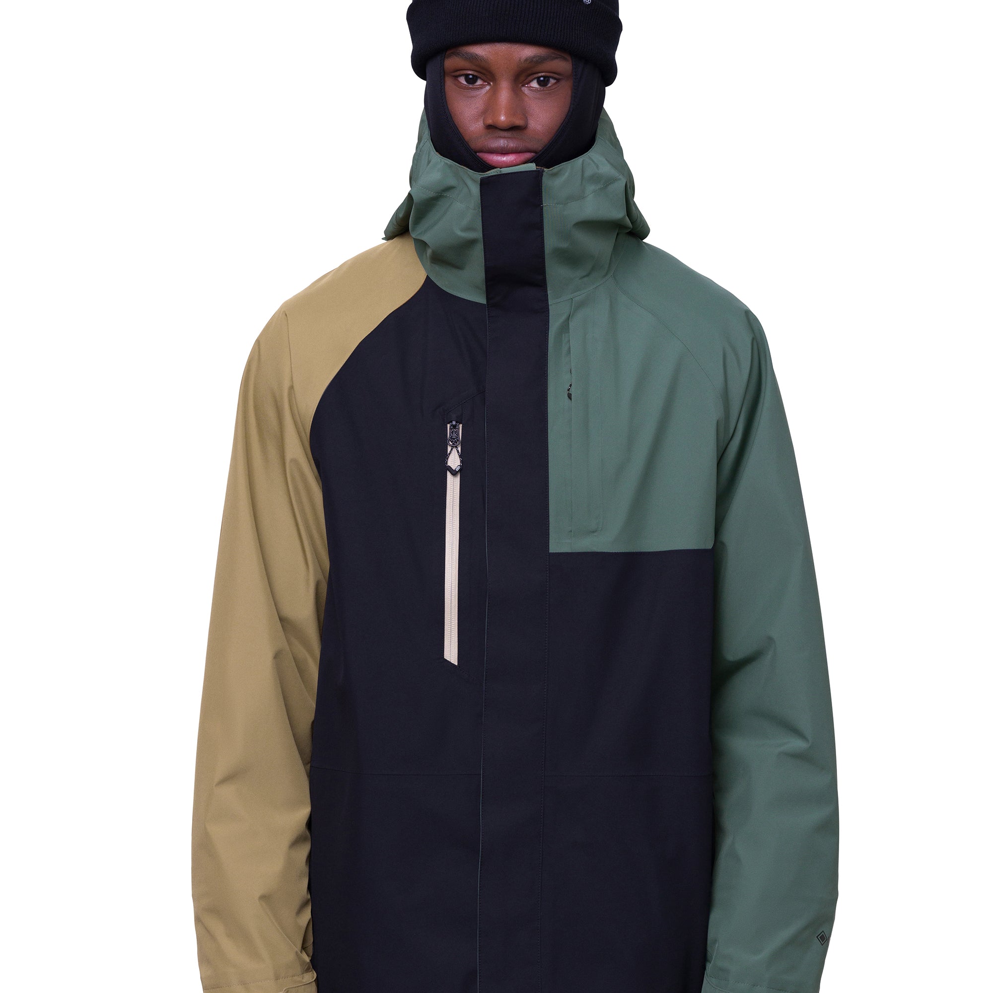 The 686 Gore-Tex Core Shell Jacket in black, tan, and green has a zippered front with two front pockets under a hood.