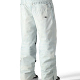 The 686 Deconstructed Denim Insulated Pant 2025 is light blue with an adjustable waistband and zippered pockets.