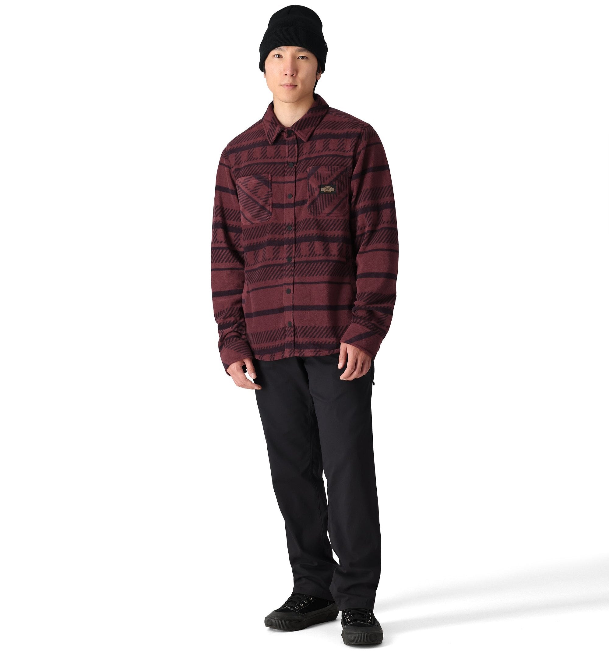 The 686 brand Sierra Fleece Flannel 2025 is showcased in this image, featuring a dark red and black plaid pattern on the front.