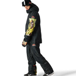 The 686 Renewal Insulated Anorak Jacket 2025 is black with an oversized hoodie and a bold graphic on the sleeve.