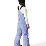 The 686 Girl's Sierra Insulated Bib Pant, shown from the back, is light blue with black suspenders and a white tag on the right side seam.