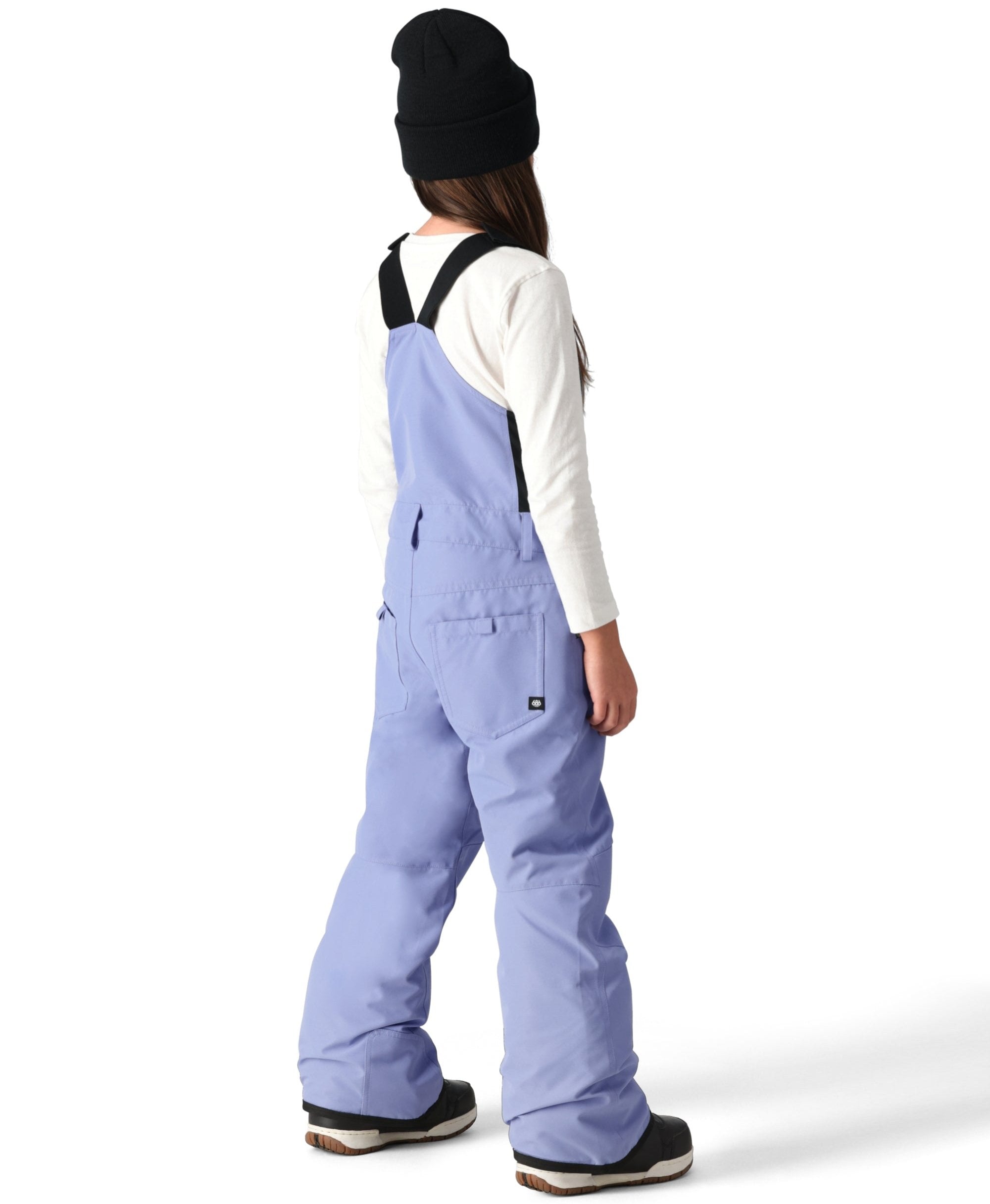 The 686 Girl's Sierra Insulated Bib Pant, shown from the back, is light blue with black suspenders and a white tag on the right side seam.