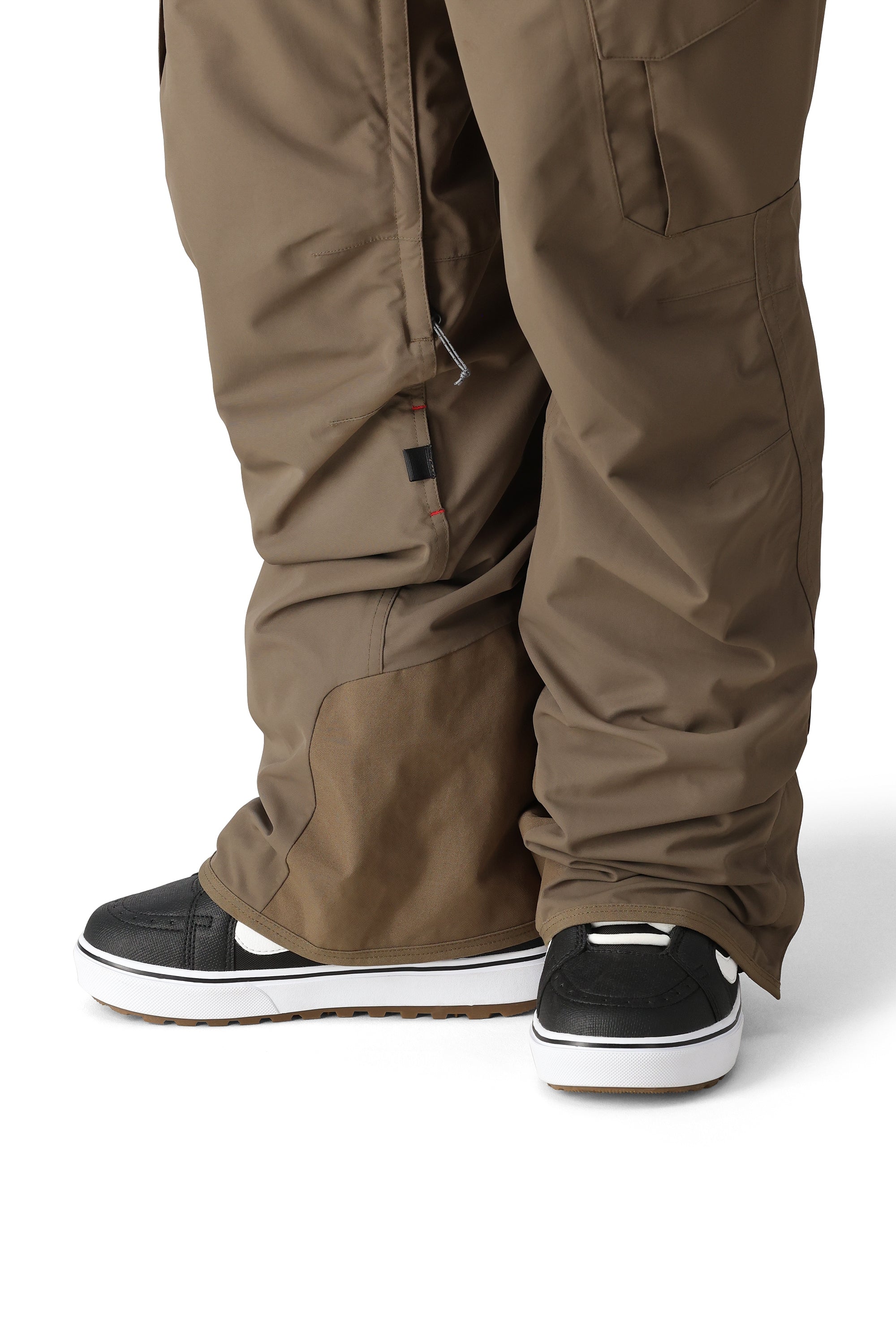 The 686 brand SMARTY 3-in-1 Cargo Pant in brown features cargo pockets on each thigh and has an adjustable waistband with a zipper fly.