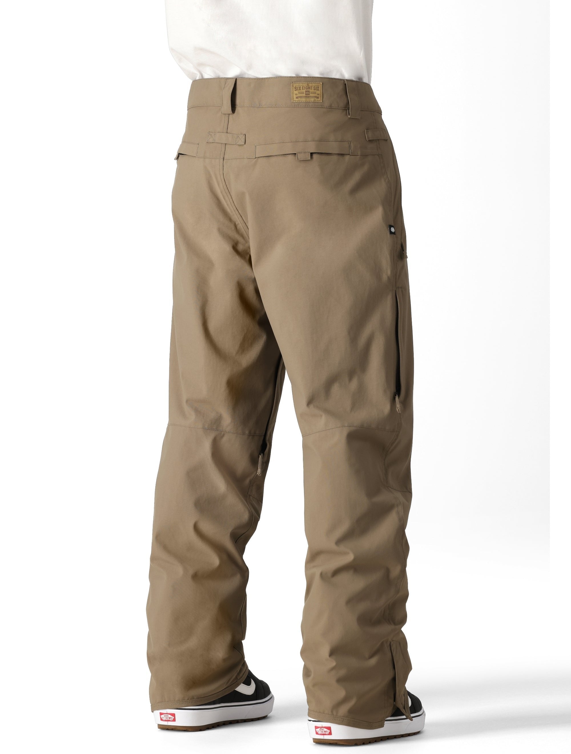 The 686 Men's Standard Shell Pant 2025 is shown in a light brown color with two zippered cargo pockets on each side.