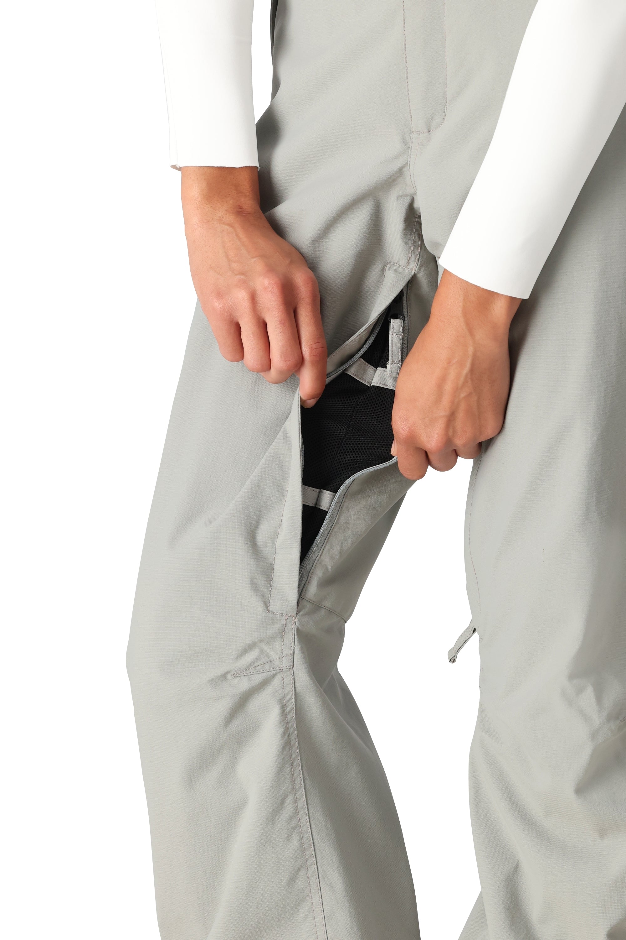 The 686 Women's Standard Shell Pant 2025 is primarily light gray with a black mesh lining visible through the split at the seam on the left leg.