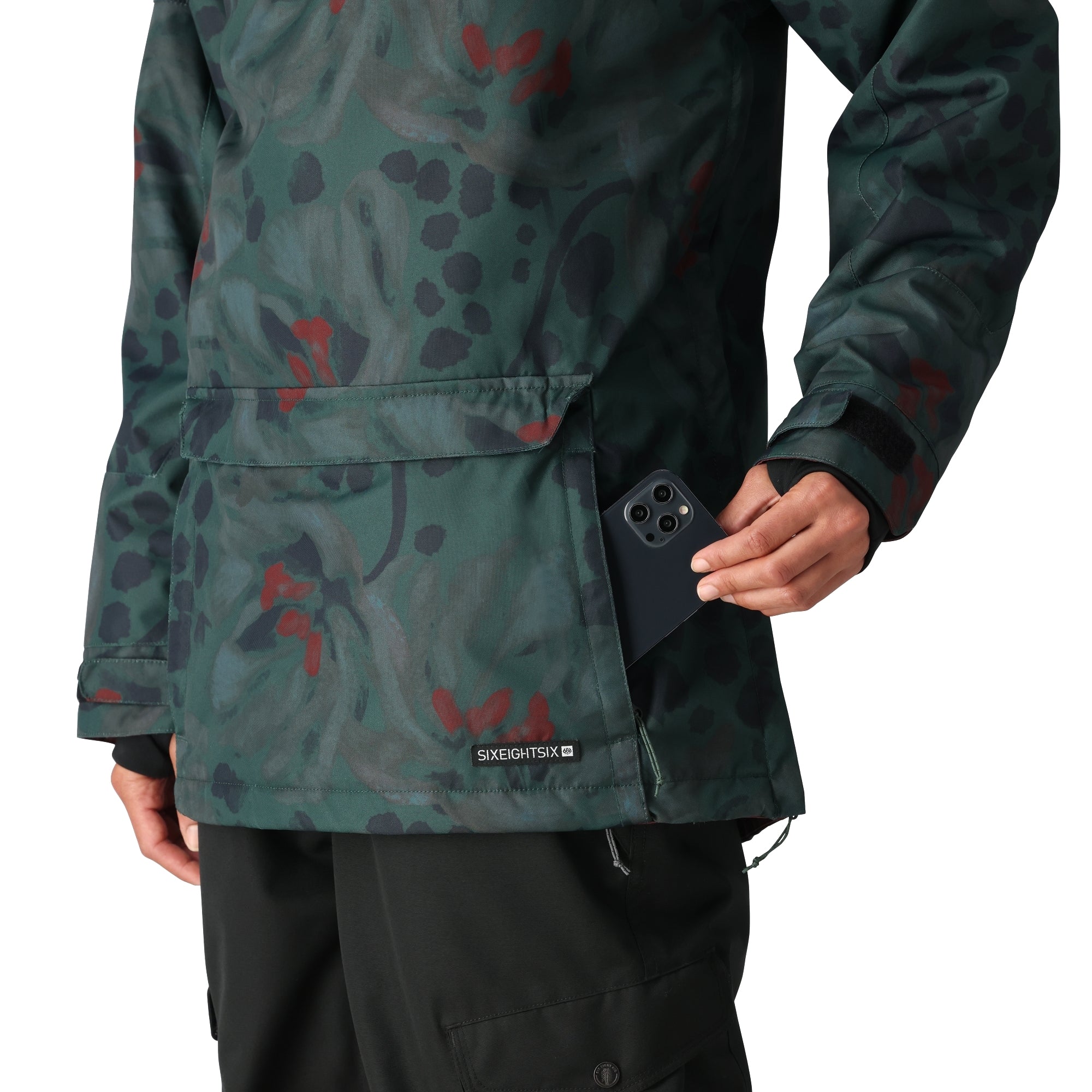 The 686 brand women's Upton insulated anorak jacket has a green floral pattern with red flowers and black leaves on a dark background.