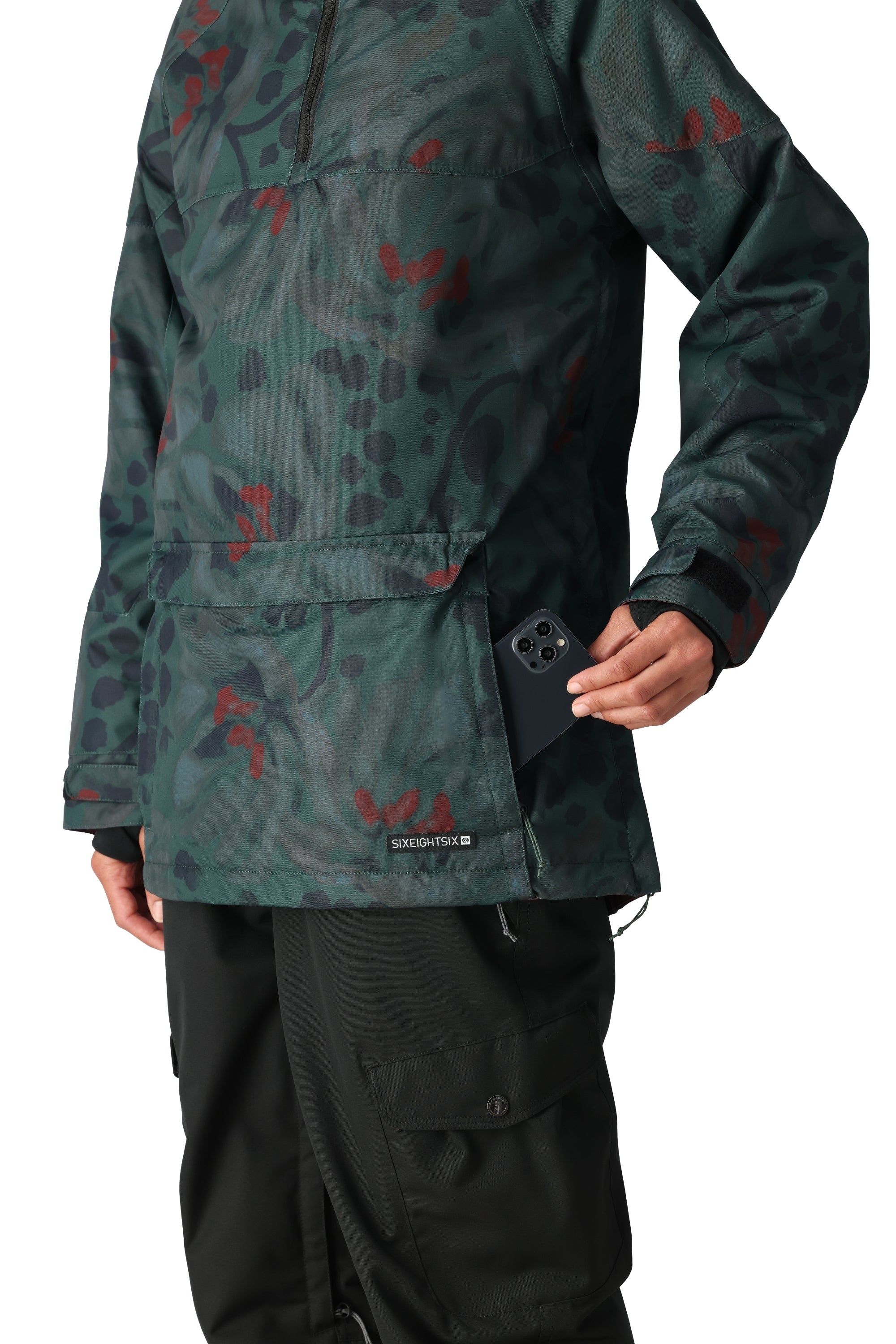The 686 brand women's Upton insulated anorak jacket has a green floral pattern with red flowers and black leaves on a dark background.