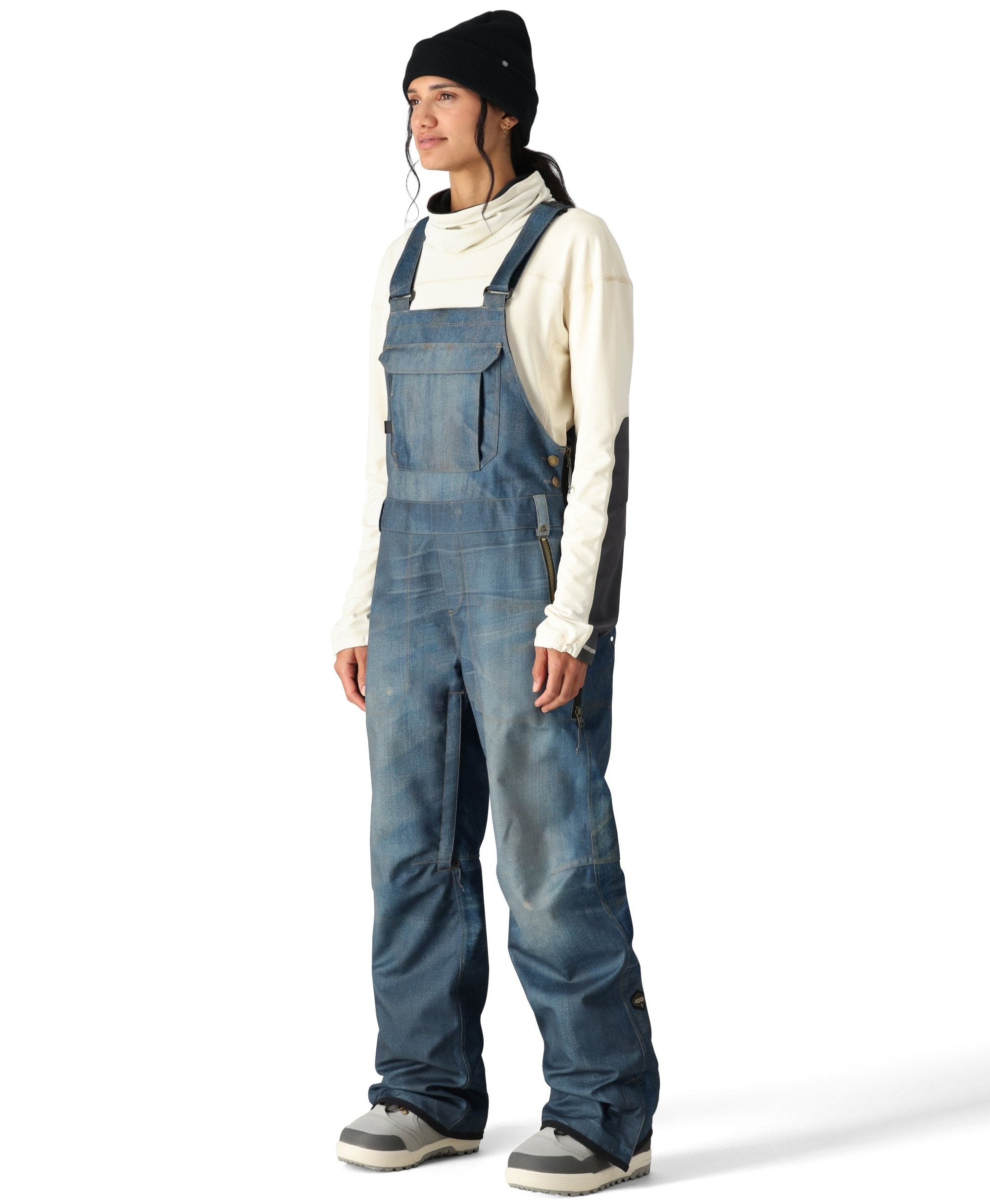 The 686 Women's Black Magic 20K Shell Bib, as seen from the front view, is a blue bib pant with a high waist and adjustable straps.