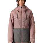 The 686 Athena Insulated Jacket in dusty rose and grey has a patterned chest section, black drawstrings on the hood, and a pink zipper down the front.