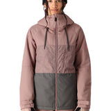 The 686 Athena Insulated Jacket in dusty rose and grey has a patterned chest section, black drawstrings on the hood, and a pink zipper down the front.