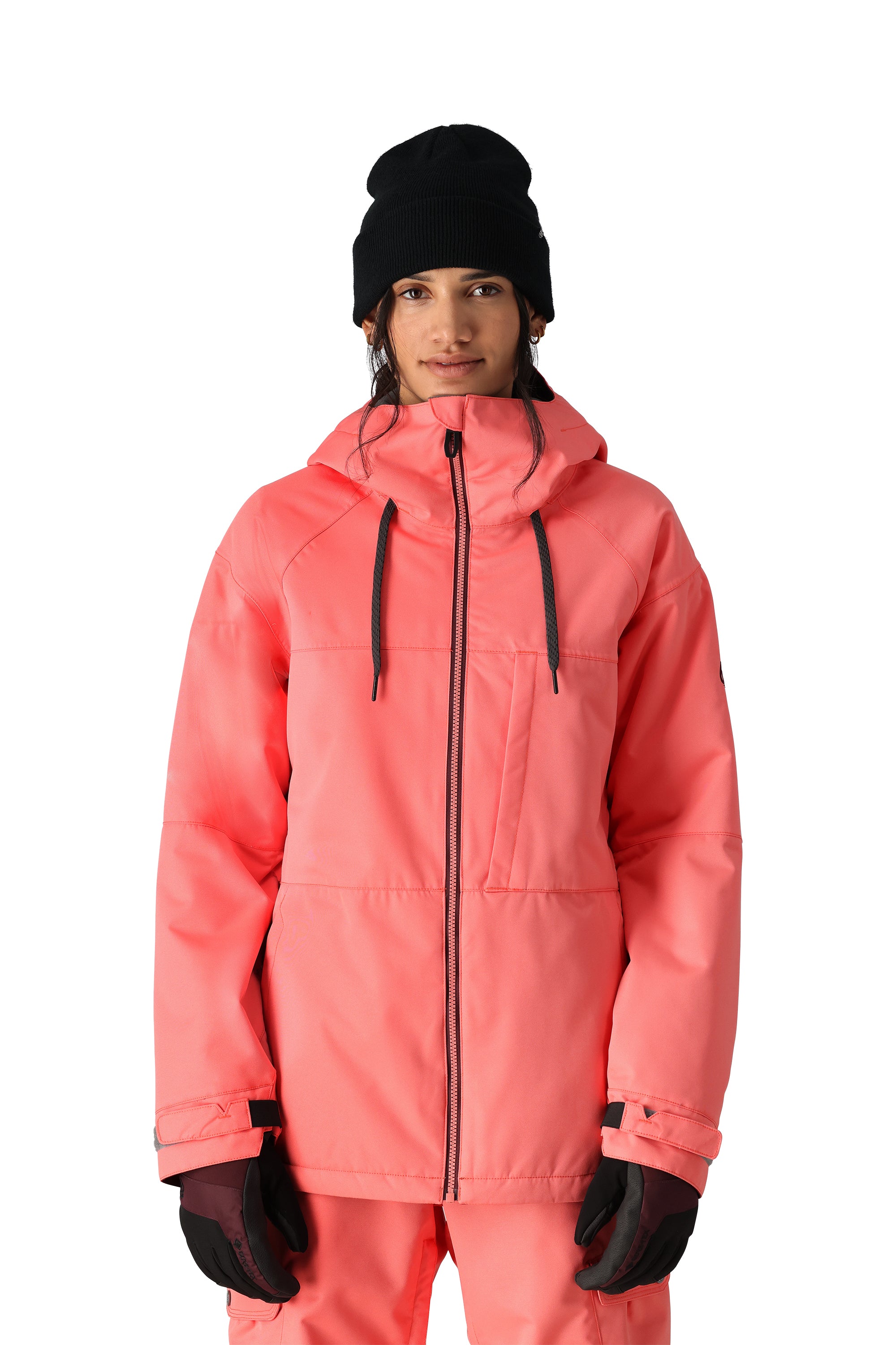 The 686 Women's Athena Insulated Jacket 2025 is showcased in this front view image, wearing a vibrant coral color with black drawstrings and a prominent hood.