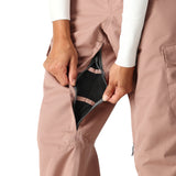 The 686 Women's Aura Insulated Cargo Pant 2025 is shown from the front view in dusty rose, featuring black mesh lining and a zippered fly.