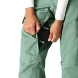 The 686 brand's 2025 model women's insulated cargo pant is showcased in a green color with two side cargo pockets.