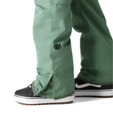 The 686 brand's Women's Aura Insulated Cargo Pant 2025 is showcased in this image, with a visible sage green color and cargo pockets.