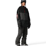 The 686 Aura Insulated Cargo Pant features a black and dark gray color scheme with a cargo pocket on one leg.