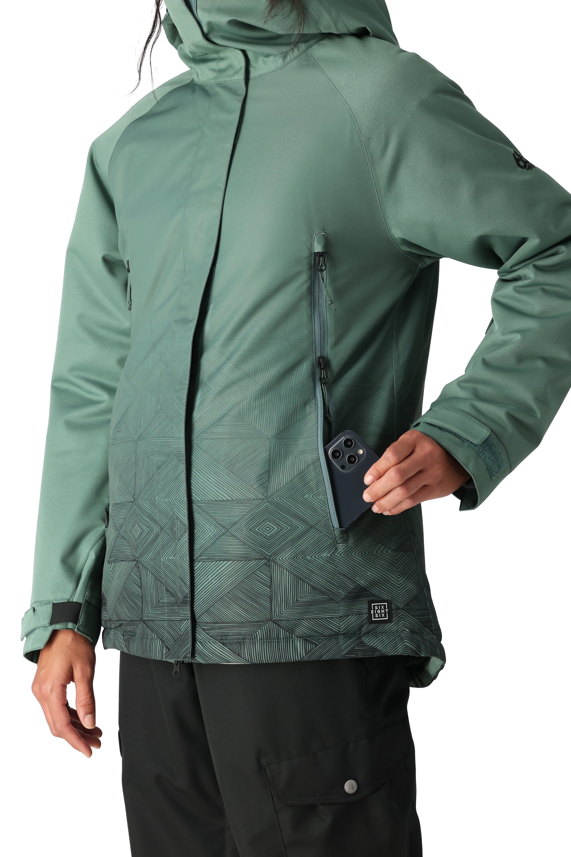The 686 Women's Fantasia Insulated Jacket 2025 is depicted in a dark green color with a pattern on the lower portion and has a zippered chest pocket.