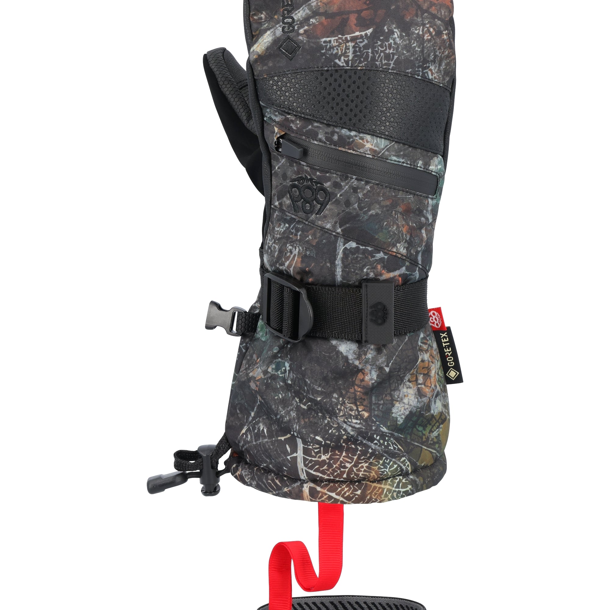 The 686 brand offers a women's GORE-TEX SMARTY 3-in-1 gauntlet mitt in a camouflage pattern with black trim and accents, featuring a red pull tab on the wrist strap.